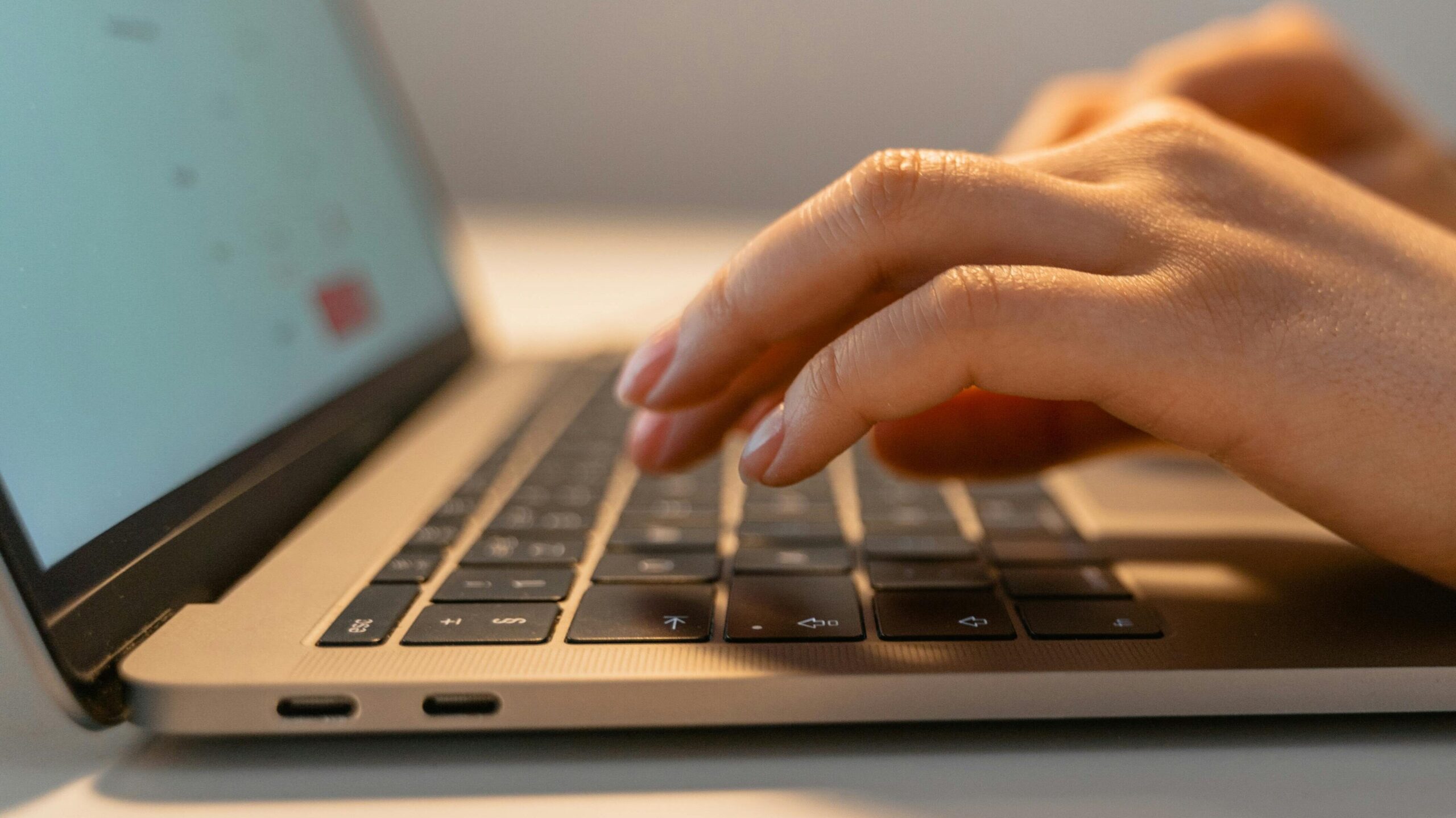 Close-up view of hands typing on a laptop keyboard, illustrating the concept of remote work and technology.